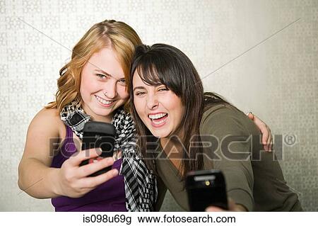 Teenage girls photographing themselves with smartphone View Large Photo Image Stock Image - Teenage girls photographing themselves with smartphone. Fotosearch