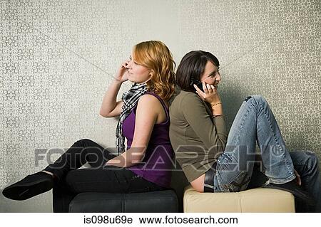 Stock Image - Teenage girls using smartphones. Fotosearch