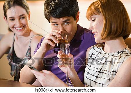 Stock Image - Three friends drinking in a bar. Fotosearch