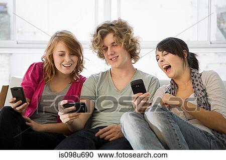 Three teenage friends looking at smartphones View Large Photo Image Stock Image - Three teenage friends looking at smartphones. Fotosearch