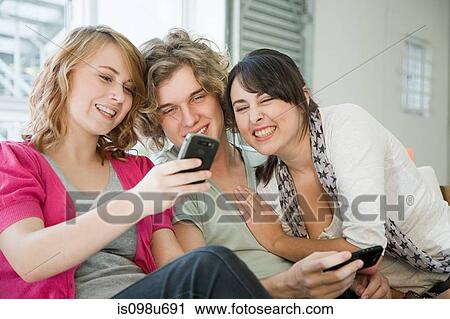 Stock Image - Three teenage friends looking at smartphone. Fotosearch