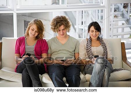 Three teenagers texting on smartphones View Large Photo Image Stock Photo - Three teenagers texting on smartphones. Fotosearch