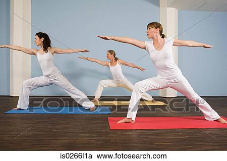 Stock Image - Three women practising yoga. Fotosearch