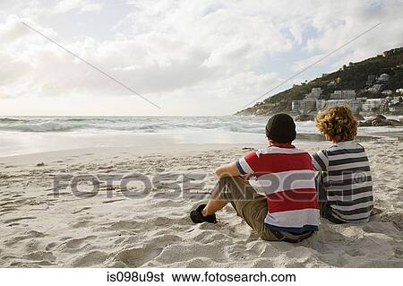 Two boys sitting on beach View Large Photo Image Stock Photograph - Two boys sitting on beach. Fotosearch