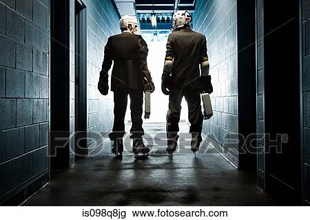 Stock Image - Two businessmen wearing ice hockey uniforms. Fotosearch