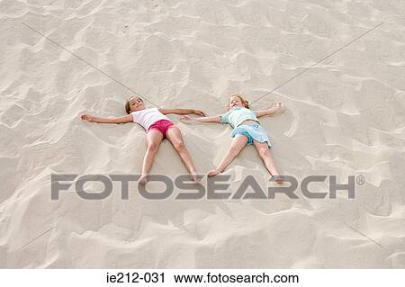 Two girls lying on a beach View Large Photo Image Stock Image - Two girls lying on a beach. Fotosearch