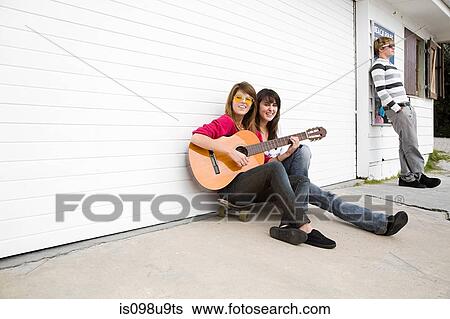 Two girls sitting on floor with guitar View Large Photo Image Stock Photograph - Two girls sitting on floor with guitar. Fotosearch