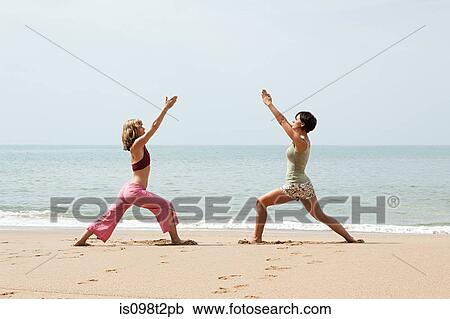 Two women practicing yoga on a beach View Large Photo Image Stock Image - Two women practicing yoga on a beach. Fotosearch