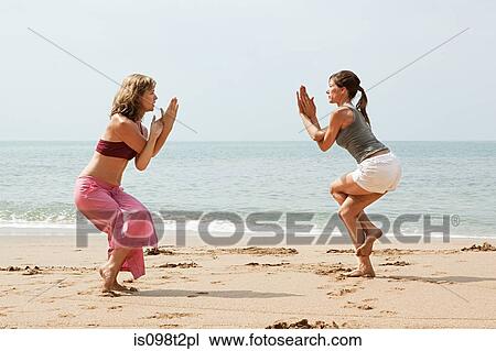 Two women practicing yoga on a beach View Large Photo Image Stock Image - Two women practicing yoga on a beach. Fotosearch