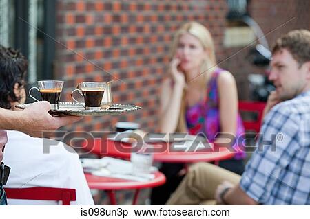 Stock Photography - Waiter with coffee for people outside cafe. Fotosearch