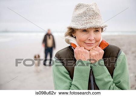 Stock Photo - Woman at the beach, man and dog in background. Fotosearch