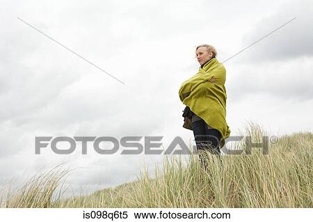 Stock Photography - Woman at the coast in blanket. Fotosearch