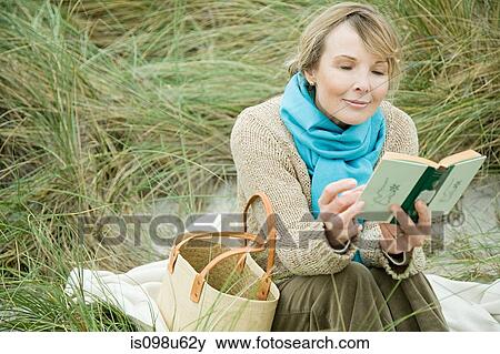 Woman at the coast reading a book View Large Photo Image Stock Photo - Woman at the coast reading a book. Fotosearch