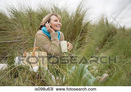Woman at the coast with mug and cellphone View Large Photo Image Stock Image - Woman at the coast with mug and cellphone. Fotosearch