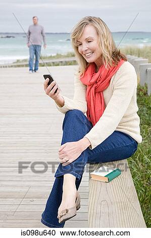 Woman at the coast with smartphone View Large Photo Image Stock Image - Woman at the coast with smartphone. Fotosearch