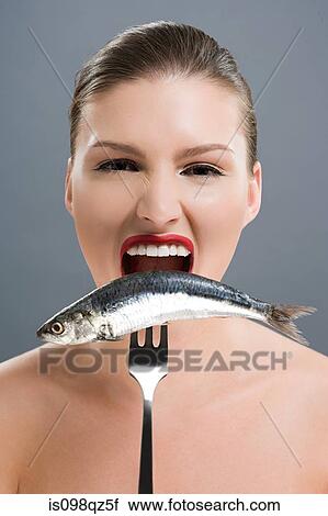 Woman biting a fish on a fork View Large Photo Image Stock Image - Woman biting a fish on a fork. Fotosearch