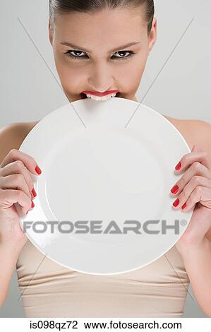 Stock Image - Woman biting a plate. Fotosearch