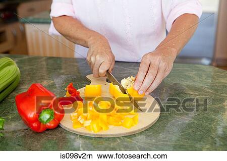 Picture - Woman chopping peppers on chopping board. Fotosearch