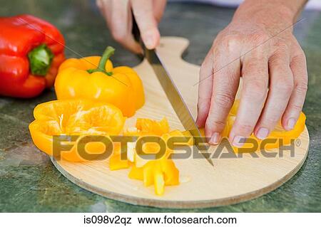 Stock Photo - Woman chopping peppers on chopping board. Fotosearch