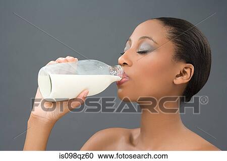 Stock Image - Woman drinking a bottle of milk. Fotosearch