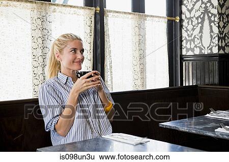 Stock Photograph - Woman having a drink at coffee shop. Fotosearch