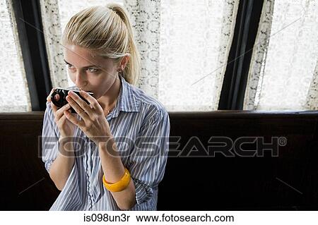 Stock Photography - Woman having a drink at coffee shop. Fotosearch