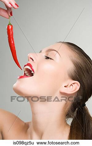 Woman holding a red chili pepper near her mouth View Large Photo Image Stock Photograph - Woman holding a red chili pepper near her mouth. Fotosearch