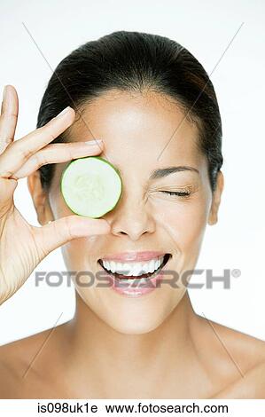 Stock Image - Woman holding cucumber over eye. Fotosearch