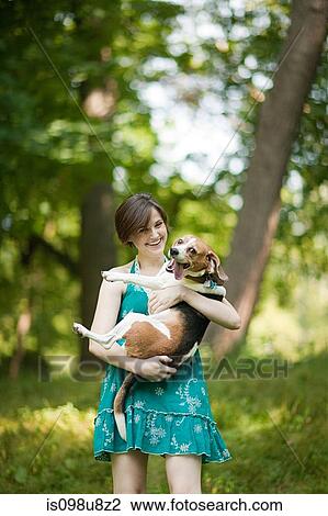 Stock Image - Woman holding her pet beagle. Fotosearch