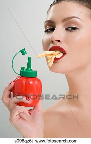 Woman holding tomato ketchup and eating fries View Large Photo Image Stock Image - Woman holding tomato ketchup and eating fries. Fotosearch