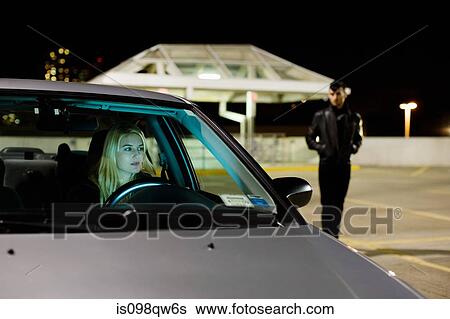 Stock Photograph - Woman in car and man in parking lot. Fotosearch