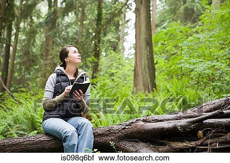 Stock Image - Woman in forest with notebook. Fotosearch