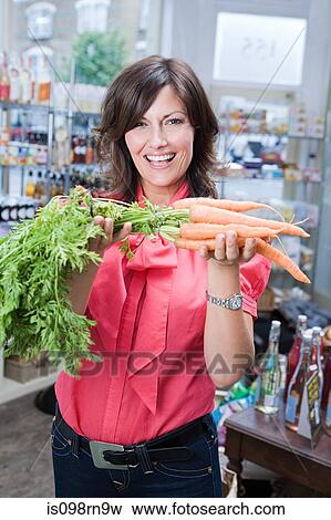 Stock Photo - Woman in store with carrots. Fotosearch