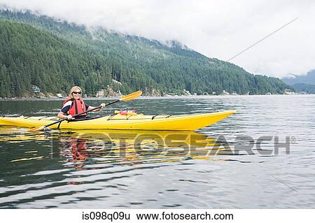 Stock Photograph - Woman kayaking in fjord. Fotosearch