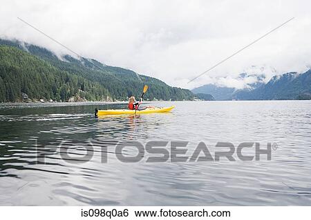 Stock Photograph - Woman kayaking in fjord. Fotosearch