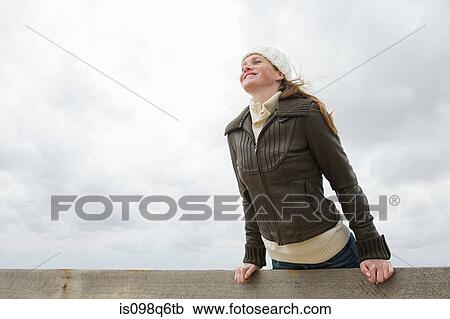 Stock Image - Woman leaning over wall. Fotosearch