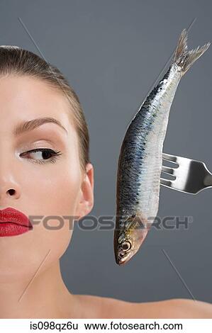 Woman looking at a fish on a fork View Large Photo Image Stock Photograph - Woman looking at a fish on a fork. Fotosearch