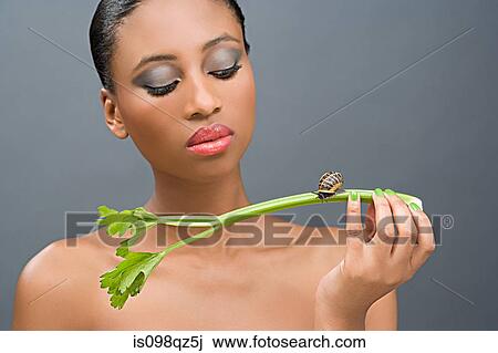 Woman looking at a snail on a stick of celery View Large Photo Image Stock Image - Woman looking at a snail on a stick of celery. Fotosearch