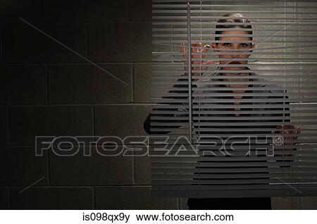 Stock Photo - Woman looking through blinds. Fotosearch