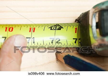 Stock Photograph - Woman measuring plank of wood and marking with pencil. Fotosearch