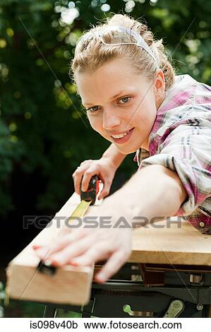 Download Woman measuring plank of wood Stock Image | is098v40b | Fotosearch