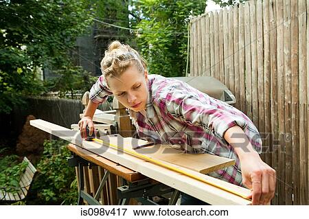 Stock Photo - Woman measuring plank of wood. Fotosearch