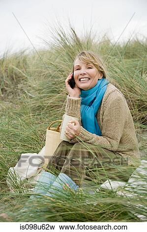 Woman on dune with mug and cellphone View Large Photo Image Stock Photo - Woman on dune with mug and cellphone. Fotosearch