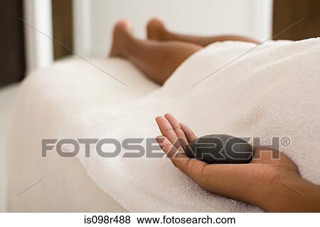 Woman on massage table holding stone View Large Photo Image Stock Photo - Woman on massage table holding stone. Fotosearch