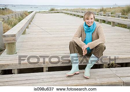 Stock Photo - Woman on walkway at the coast. Fotosearch