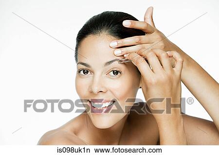 Picture - Woman plucking her eyebrows. Fotosearch