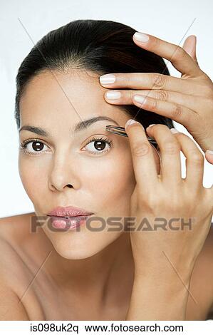 Stock Photography - Woman plucking her eyebrows. Fotosearch