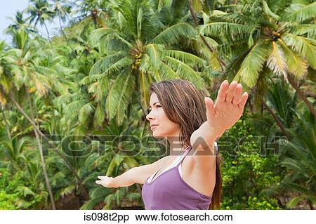 Stock Photography - Woman practicing yoga by palm trees. Fotosearch
