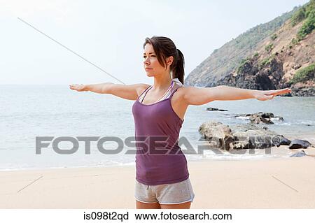 Stock Image - Woman practicing yoga by sea. Fotosearch