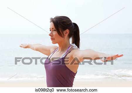 Stock Image - Woman practicing yoga by the sea. Fotosearch